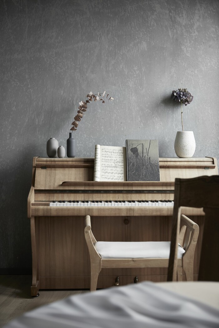 Piano och stolar från Anjas barndomshem. Den vita vasen från The Clay lab i Malmö, som drivs av keramikern Stella Brudin. piano och väggar av betong
