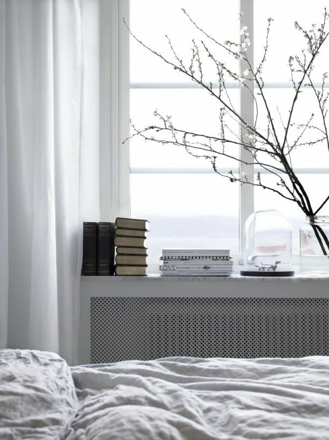 En trave böcker ligger på fönsterblecket i sovrummet. Tommy_Residence_3