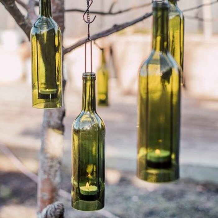 Bryt av det naturnära och gör din egen hänglykta av glasflaskor. Häng flaskorna i olika höjd för ett dynamiskt, mer levande intryck. Foto: Granit. Trender för balkong och uteplats sommaren 2021