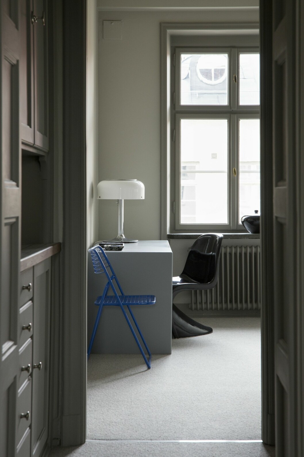 Det forna köket är i dag parets arbetsrum. Skrivbordet från Montana har sprejmålats. Anders Pehrsons bordslampa Knubbling, Ateljé lyktan. Svart Panton chair. Heltäckningsmatta Ackland, Golvabia. Blå nätstol i metall, second hand. Våningen med det lilla extra – hemma hos inredaren Nellie Fasth