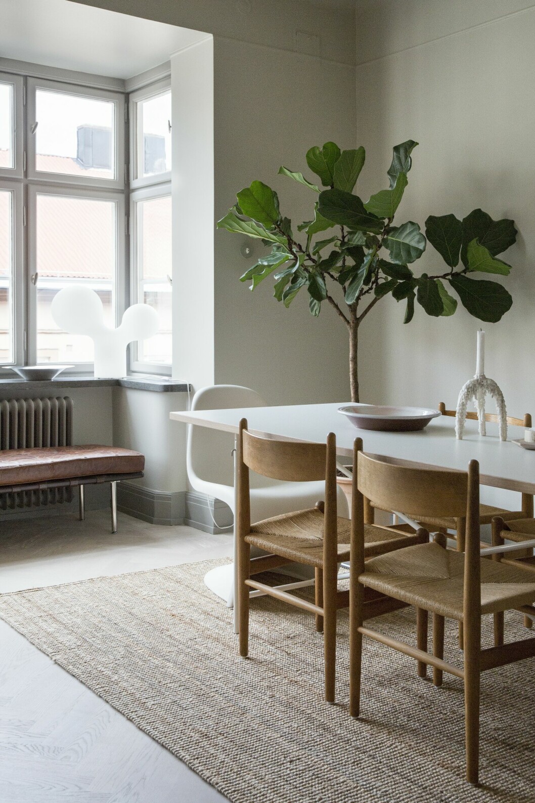 Matbord av Egon Eiermann med Wegners stolar CH36 samt vit Panton chair. Keramikfat, Hay. Ljusstake Rå av Karolina Brobeck. Matta, Ikea. Våningen med det lilla extra – hemma hos inredaren Nellie Fasth
