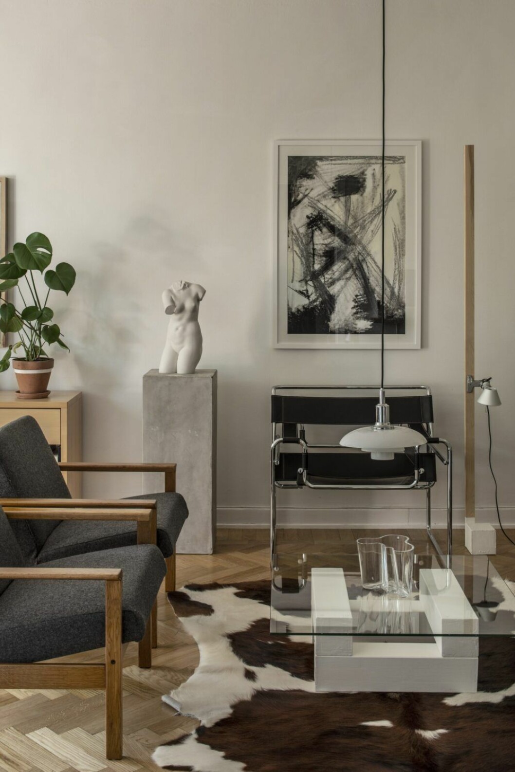 Fåtöljer Low back F06 av Yngve Ekström för Pastoe. Piedestalen är en uppochnedvänd trädkruka. Marmorskulptur, second hand. Wassily lounge chair av Marcel Breuer. Kohud från en gård i Östergötland. Soffbord tillverkat av Sebastian. Vas, Alvar Aalto, Iittala. Lampa PH 3/2 av Poul Henningsen för Louis Poulsen. Pastellteckning av Sebastian. Hemmagjord lampfot till en Tolomeo micro pinza. Vardagsrum