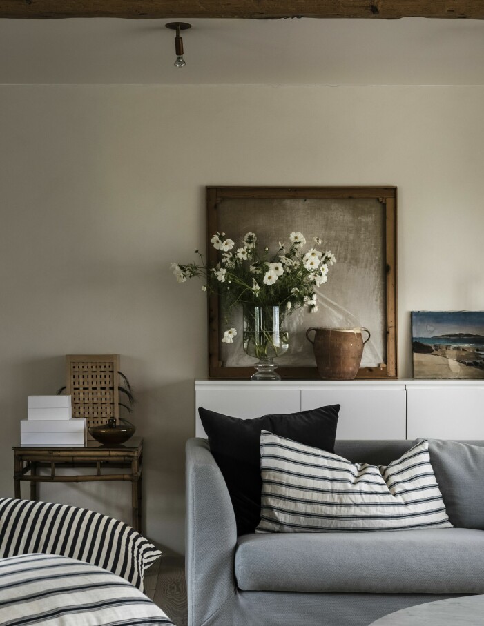 I vardagsrumsdelen en soffa från Offecct, gamla bolster och loppisfynd. Tavlan får visa sin vackra baksida. Det lilla flätade skåpet på bordet intill gjorde Lisette som ett arbete på Konstfack. Vardagsrum.