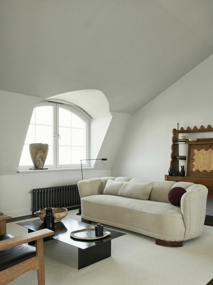 De en gång raka fönsternischerna välvdes för ett finare utseende. Skulptur, Bacchus antik. Soffbord, egen design från Wtp studios. »Soffan är en omklädd tjockis från 1940-talet och bokhyllan en helgalen skapelse av Paolo Buffa.« Vardagsrum lägenhet i Råsunda tornet.