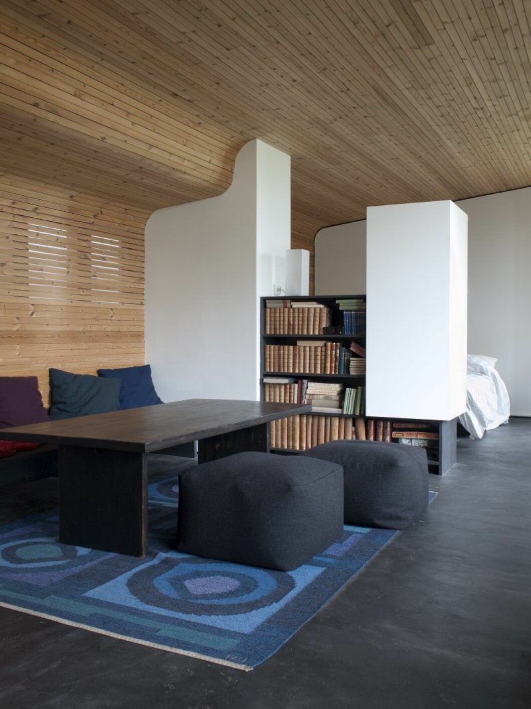 Taket böljar mjukt till vägg som hos Alvar Aalto. Obehandlad gran och furu, sågad i sågverket tvärs över viken. Dagbädden blir barnsäng på natten. Aftonsolen kan sila genom ribborna. Taket böljar mjukt till vägg som hos Alvar Aalto. Obehandlad gran och furu, sågad i sågverket tvärs över viken. Dagbädden blir barnsäng på natten. Aftonsolen kan sila genom ribborna.
