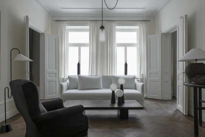 Golvlampa Roattino av Eileen Gray, från Classicon. Fåtölj och soffa från Perspective studio. Taklampa: Lariat Sconce från Apparatus studio. På bordet Neo Lantern från Apparatus. Metallvaser i fönstret Canon från Mad et Len. Sidobord och lampa vintage. Gardiner från Gotain. Vardagsrum inrett av Robin Klang grundare till Perspective studio