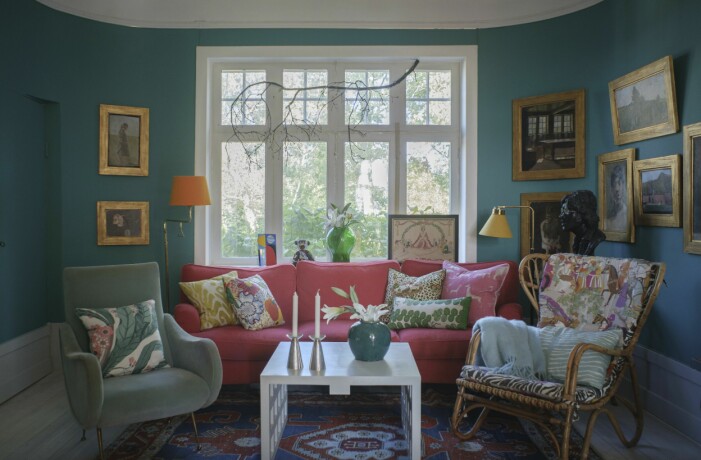 I det mindre vardagsrummet, familjens tv-rum, hänger flera verk av Marie Krøyer. Korgfåtöljens dyna är klädd i tyget Dara från Manuel Canovas. Bordet har Sanna tillverkat. Den ljusblå fåtöljen är italiensk och inköpt på en antikmässa. Familjens vardagsrum i Villa Akleja.