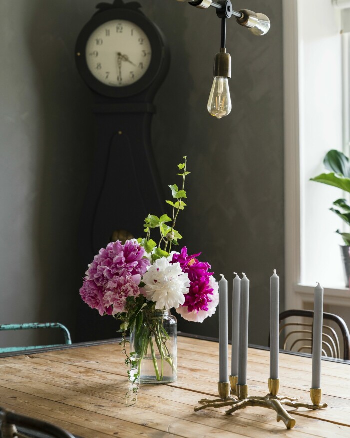 I den uppvuxna trädgården runt stationshuset växer överdådiga pioner i olika färger, som blir vackra och miljövänliga blomarrangemang med bara några kvistar grönt till. Vas med blommor på ett bord.