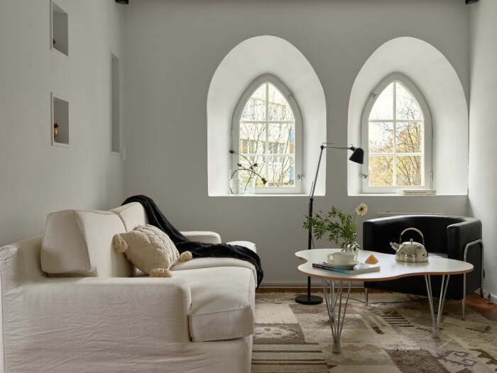 De spetsbågeformade och djupa fönstren bidrar till den klosterliknande, lugna känslan. Vattentorn till salu på Lidingö Residence magazine soffa vardagsrum