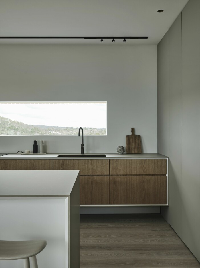 Köket är ritat av Linus och byggt av Stiligt design. Materialvalen har hållits till ett minimum vilket förstärker de fina detaljerna och inte gör intrång på den fantastiska utsikten. Bänkskåpen är väggmonterade för att ge en svävande känsla. Fronterna är i mönsterpassad ek och bänkskivan, liksom högskåpens dörrar är Fenix laminat i färgen Arizona beige. Linus Fernström hus