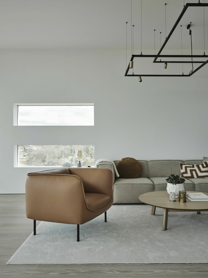 Enhetliga svarta armaturer finns i alla rum där samtliga fasta installationer kommer från Supermodular. Soffan från Bo concept och skinnfåtöljerna Gather är från Edsbyn. Soffbordet från Jysk, under ligger en matta från Golvabia. Ljust och modernt vardagsrum.