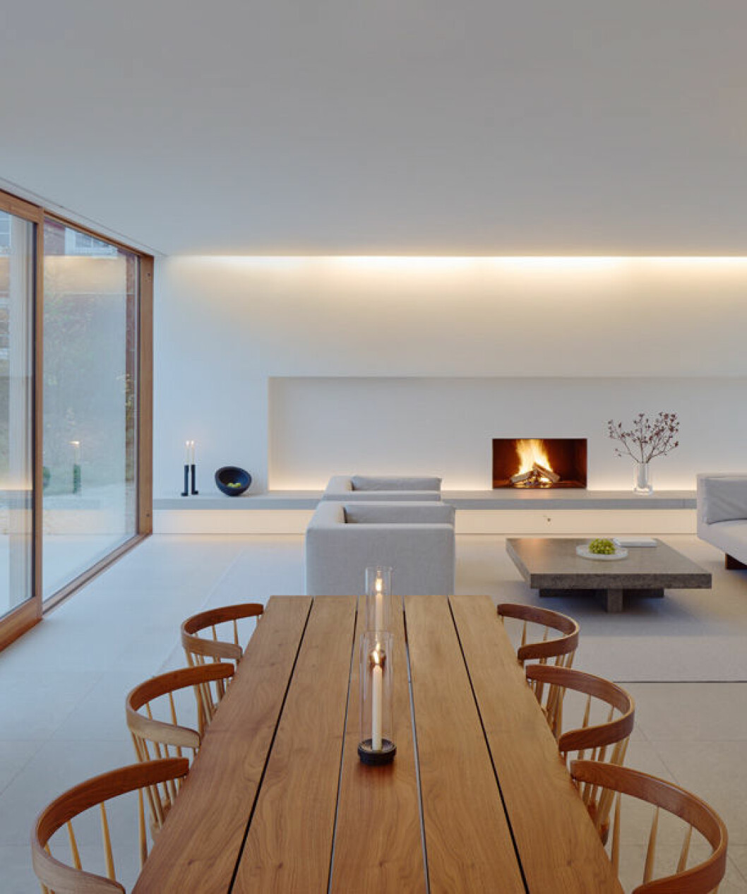 Bordet i amerikansk valnöt, designat av Pawson, kompletteras med handbyggda stolar av Nakashima. Den öppna spisen ramas in av en nisch som bland annat döljer platteven. Villa Palmgren, John Pawson Limited