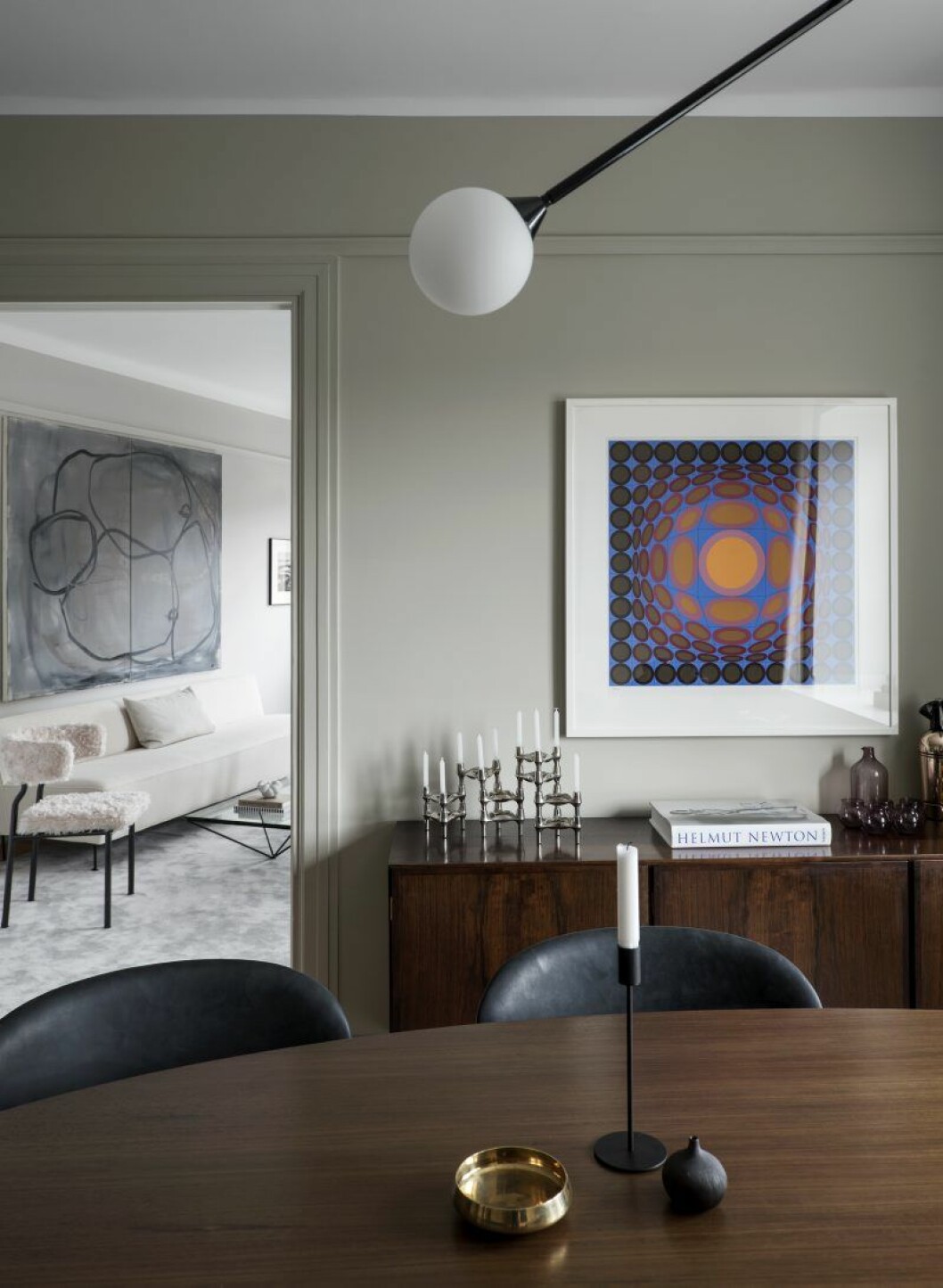 Från matsalen kommer man direkt in i vardagsrummet. På väggen en tavla av Vasarely som i färgerna matchar sideboarden. Lampa Twospheres från Areti, Hanna’s room. Wessman_5