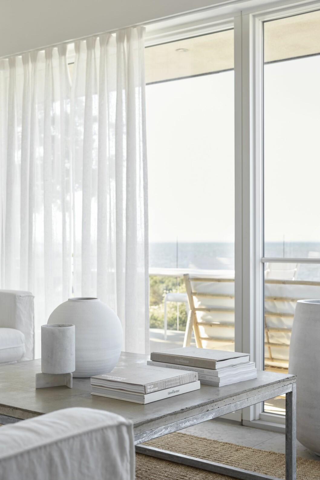 Från soffgruppen ser Anette och hennes man ut över havet. Soffa från Ikea med linneöverdrag från Bemz. Bordet med en gjuten betongskiva är hembyggt. Rund vas från By On. Kruka i marmor från 101 Copenhagen. Från soffgruppen ser man havet.
