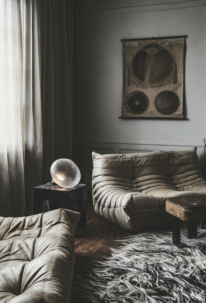 Sofforna i vardagsrummet kommer från Ligne Roset, mattan är köpt av Marie Olsson Nylander, lamporna från Art n deco. Planschen som visar ögats anatomi är från 1800-talet, pallen är vintage och lampan ovanpå är Petite friture. Soffbord, Jakobssons möbler och gardinerna är uppsydda på Syknuten. Vardagsrum med soffor och stor tavla.