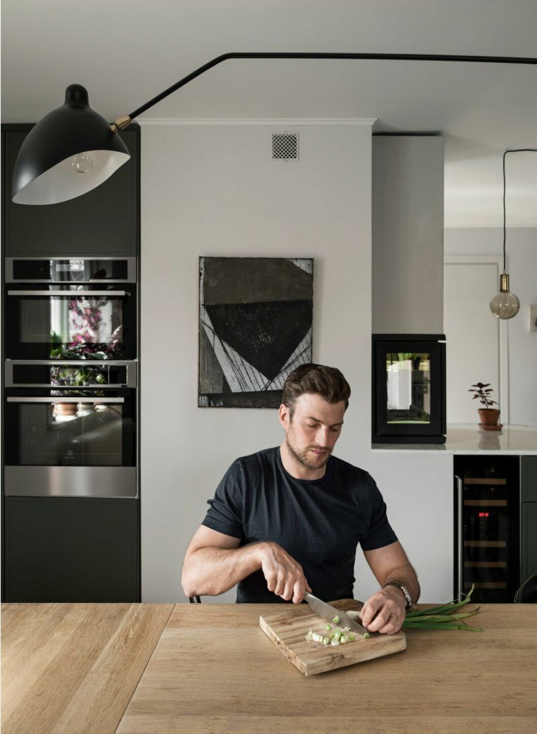 Lampa av Serge Mouille. Bänkskiva i bakgrunden av statuariomarmor och en inbyggd eldstad av glas.
