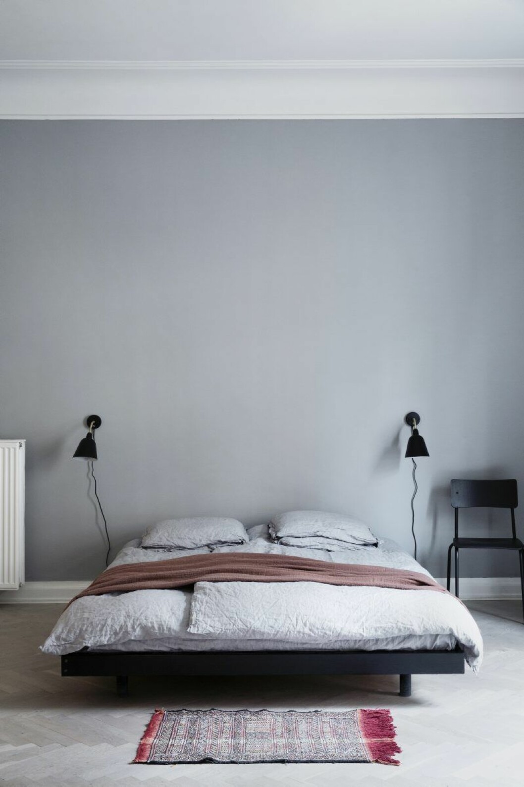 Det enkelt möblerade sovrummet är neutralt färgsatt och har en futon- säng klädd i linnelakan från Society. Pläd, Geismars. Sänglampor Bellevue, designade av Arne Jacobsen.