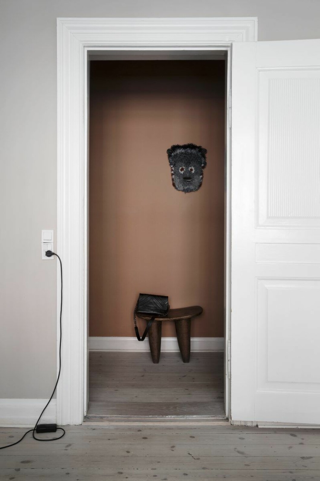 Den lilla hallen är målad i terrakottafärg. Pall från Elfenbenskusten, mask av konstnären Marianne Eriksen Scott-Hansen.